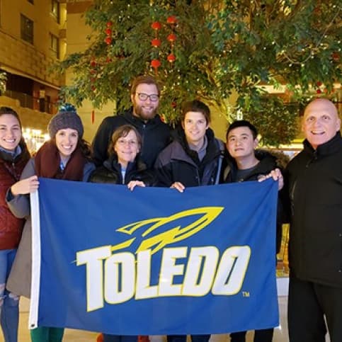 Clint with students holding a University of Toledo Flag