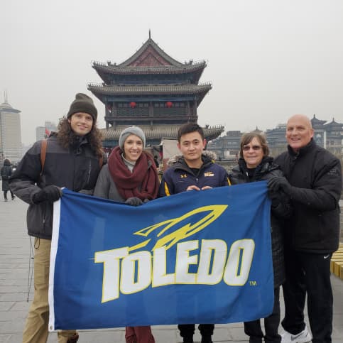 Clint in China holding University of Toledo flag